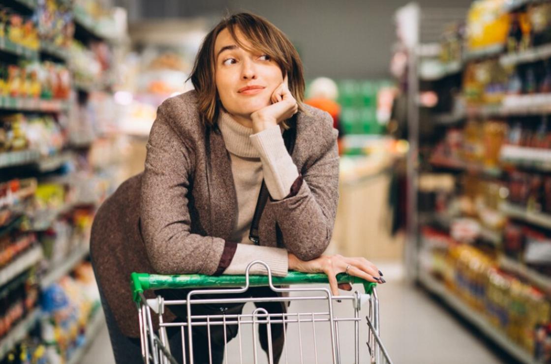 Девушка стоит с тележкой в супермаркете