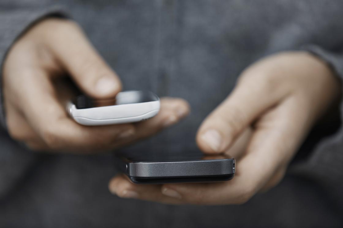 Мужчина держит в руках два смартфона