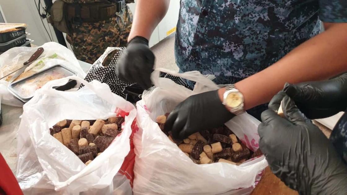 Полицейский в перчатках осматривает конфеты в пакетах