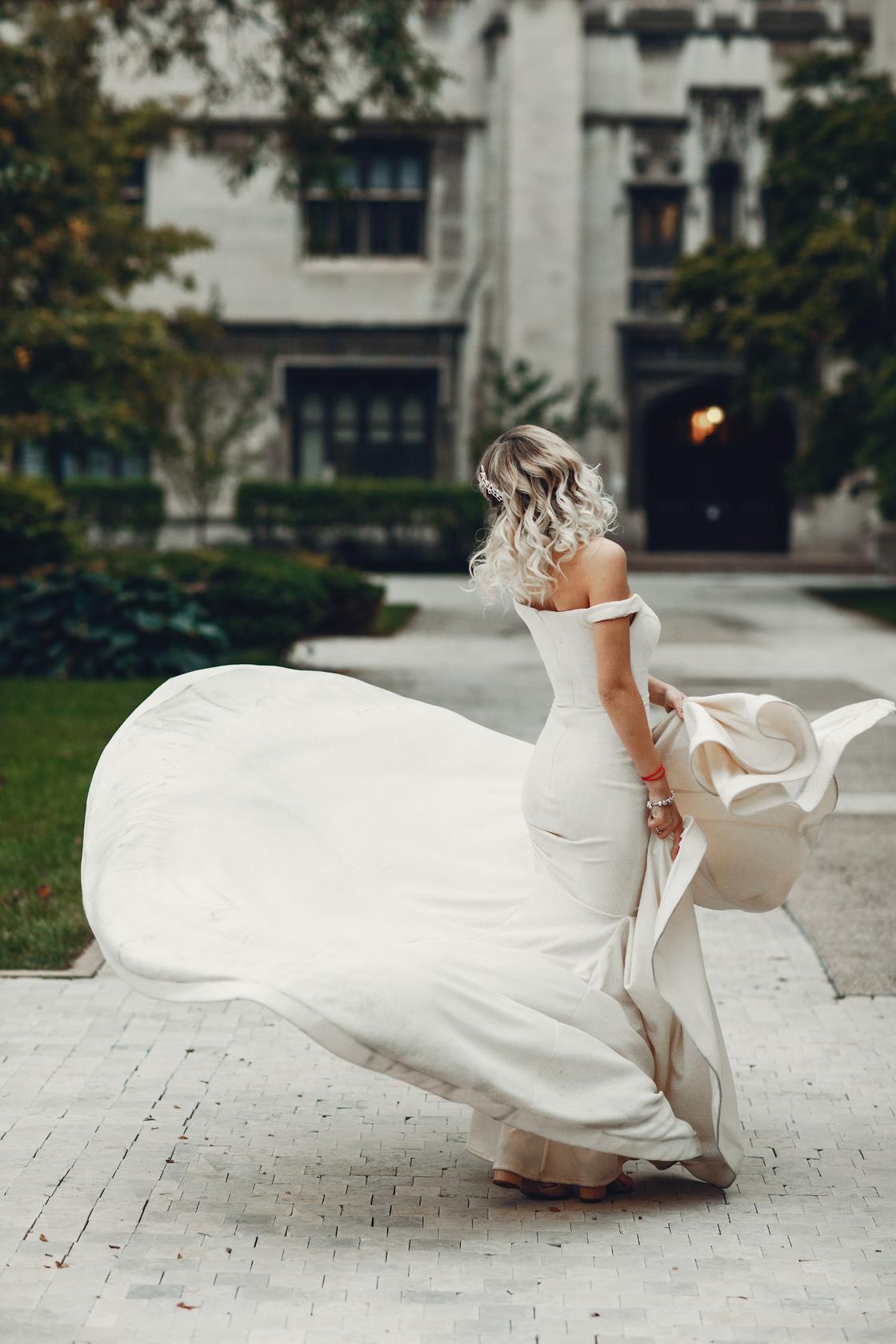 Девушка в облегающем свадебном платье гуляет на улице