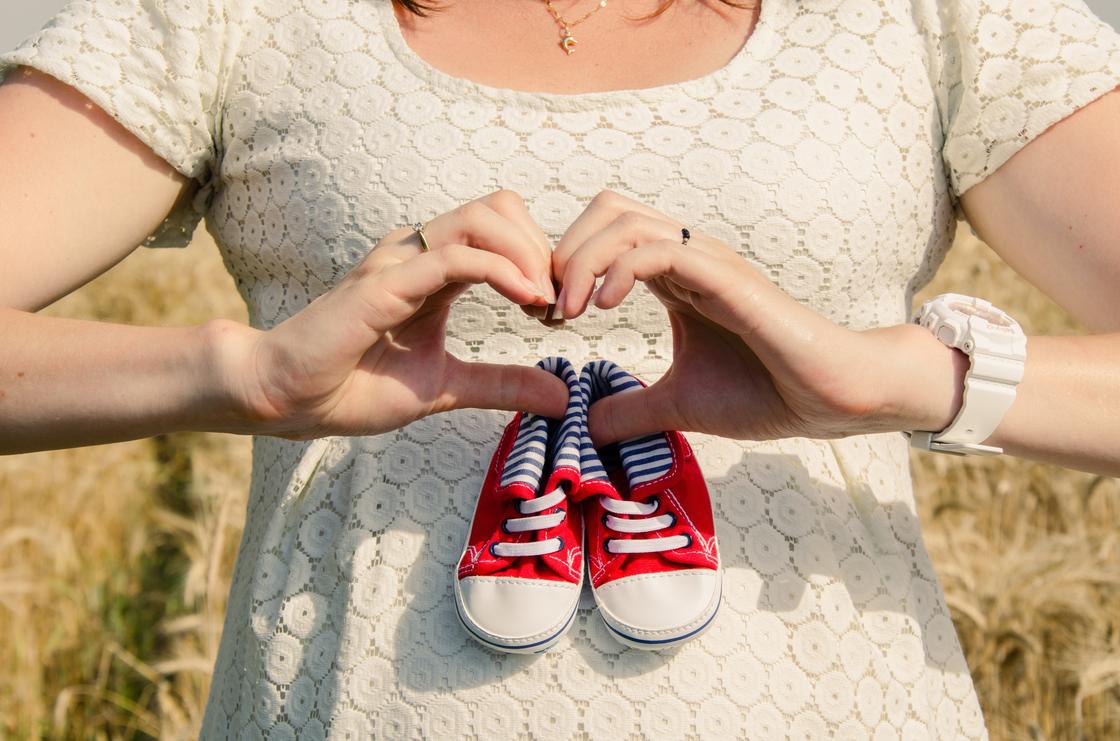 Беременная женщина держит детскую обувь