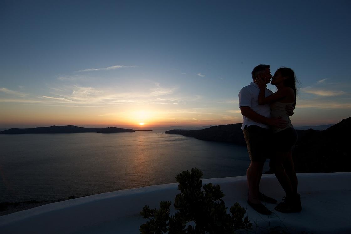 Парень и девушка целуются на закате