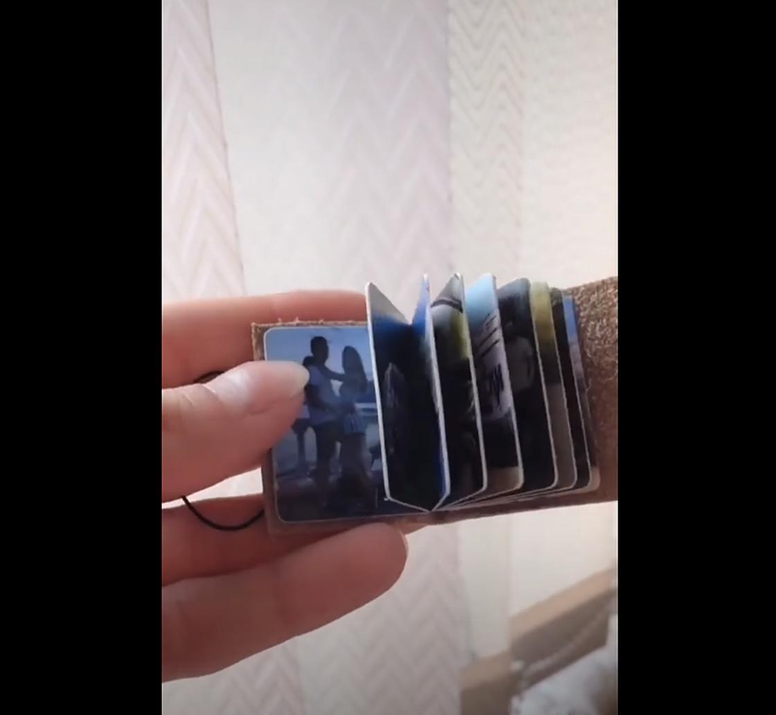 Девушка держит в руках брелок с фотографиями Девушка держит в руках брелок с фотографиями
