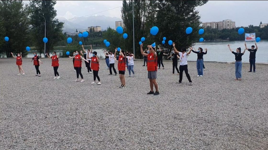 Группа людей стоит на пляже с синими воздушными шариками