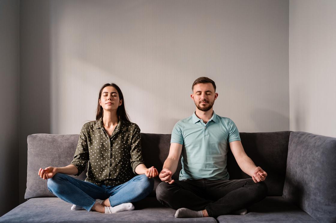 Мужчина и женщина медитируют на диване