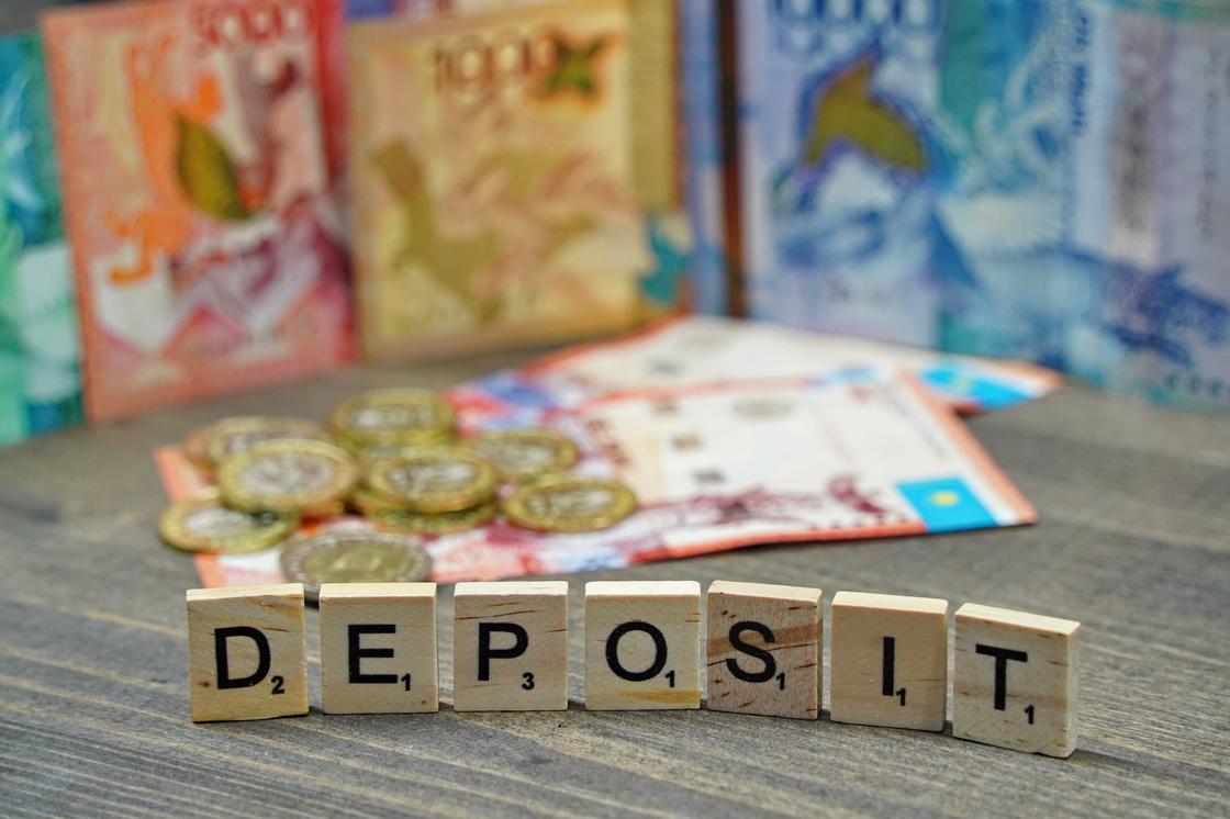 Кубики с надписью "Deposit" стоят на фоне денег