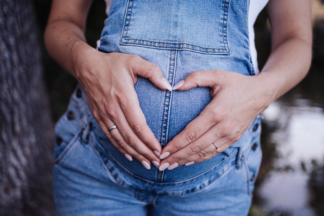 Беременная женщина в джинсовом комбинезоне