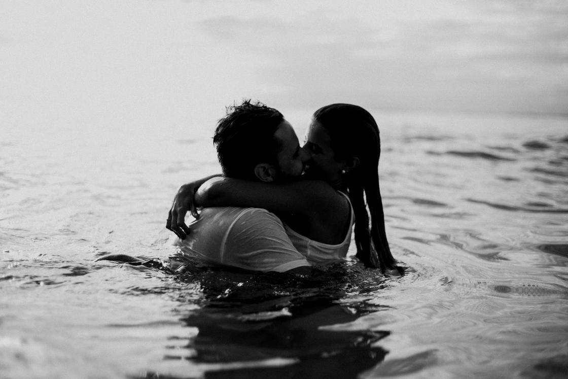 Парень и девушка целуются, стоя в воде