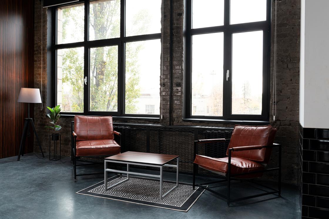 В комнате металлический стол, кожаные кресла и большие панорамные окна