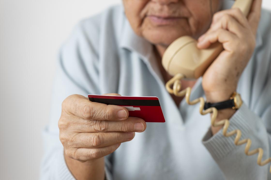 Пенсионерка держит телефон и банковскую карту