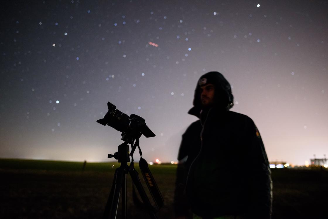 Мужчина с телескопом на фоне звездного неба