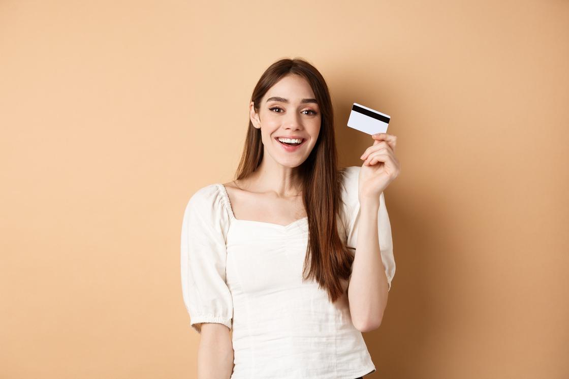 Улыбающаяся девушка держит в руках банковскую карту