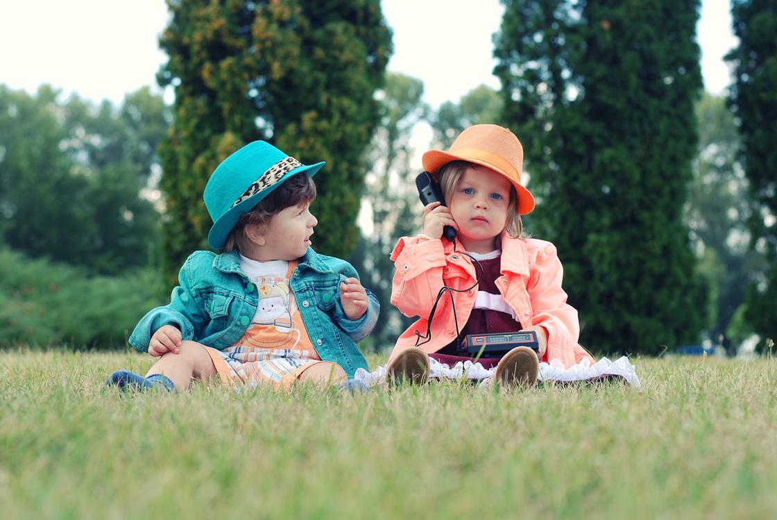 Мальчик и девочка сидят на траве