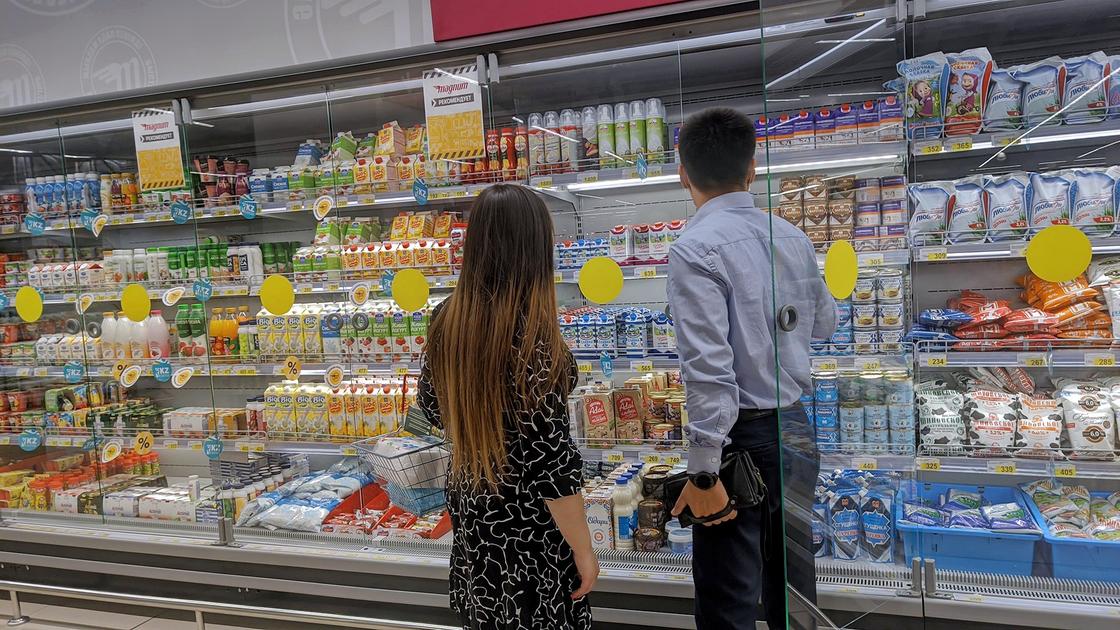 Молодая пара выбирает молоко в супермаркете