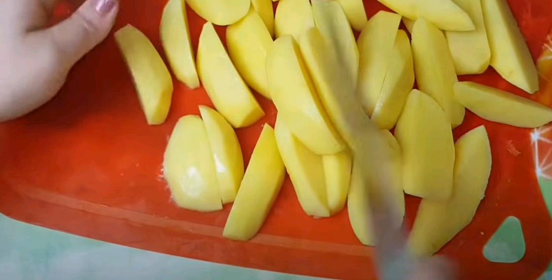 Женщина нарезает картофель для жаркого дольками Женщина нарезает картофель для жаркого дольками
