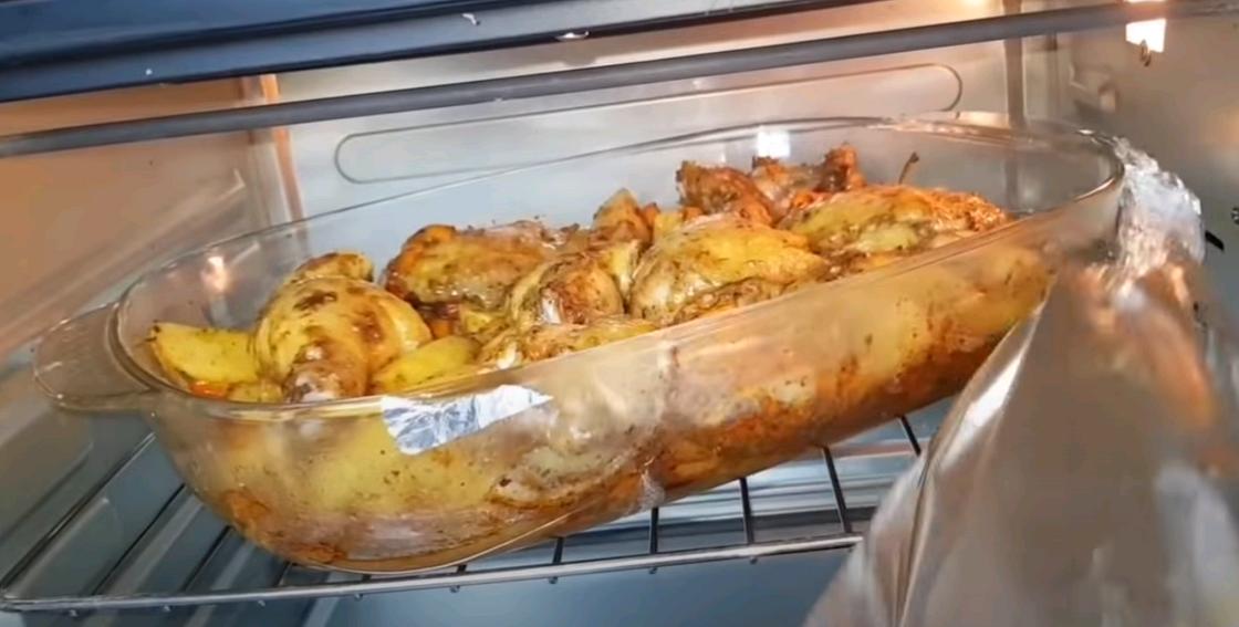 Женщина снимает фольгу с формы, где готовится жаркое Женщина снимает фольгу с формы, где готовится жаркое