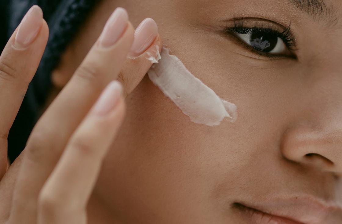 Девушка наносит защитный питательные крем на кожу лица