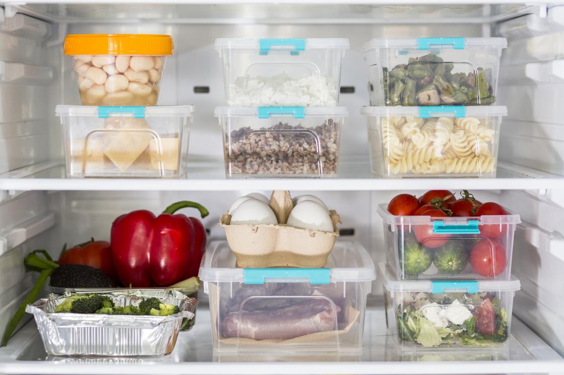 Готовые блюда, овощи, яйца сложены в отдельные контейнеры и расставлены по полкам холодильника