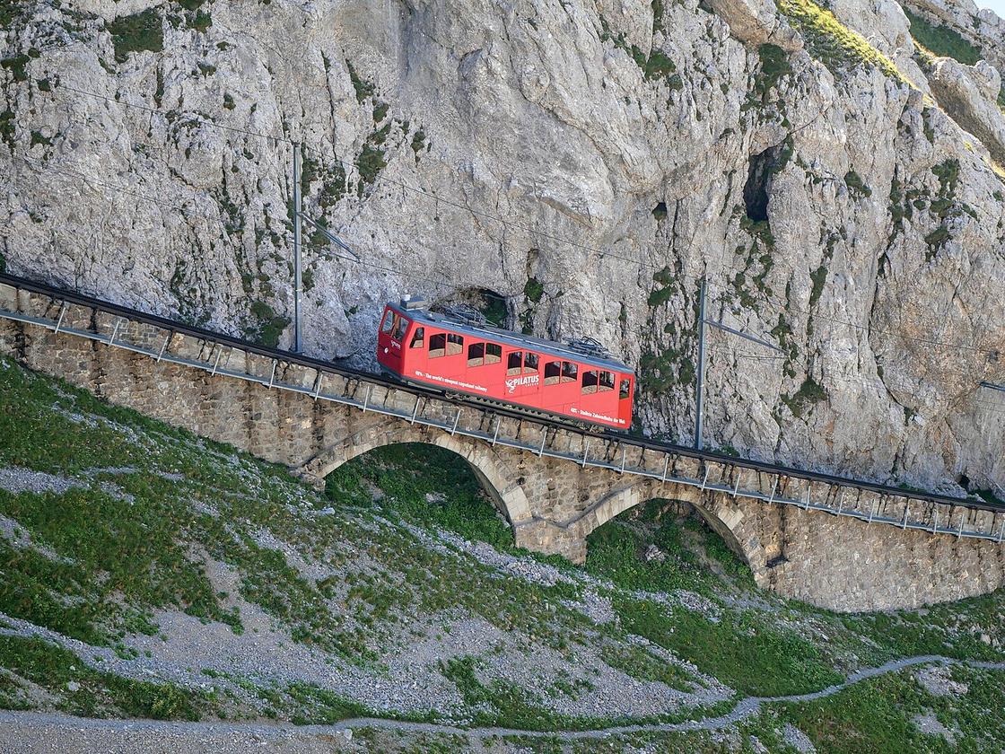 Поезд движется по наклонной дороге, расположенной в Альпах