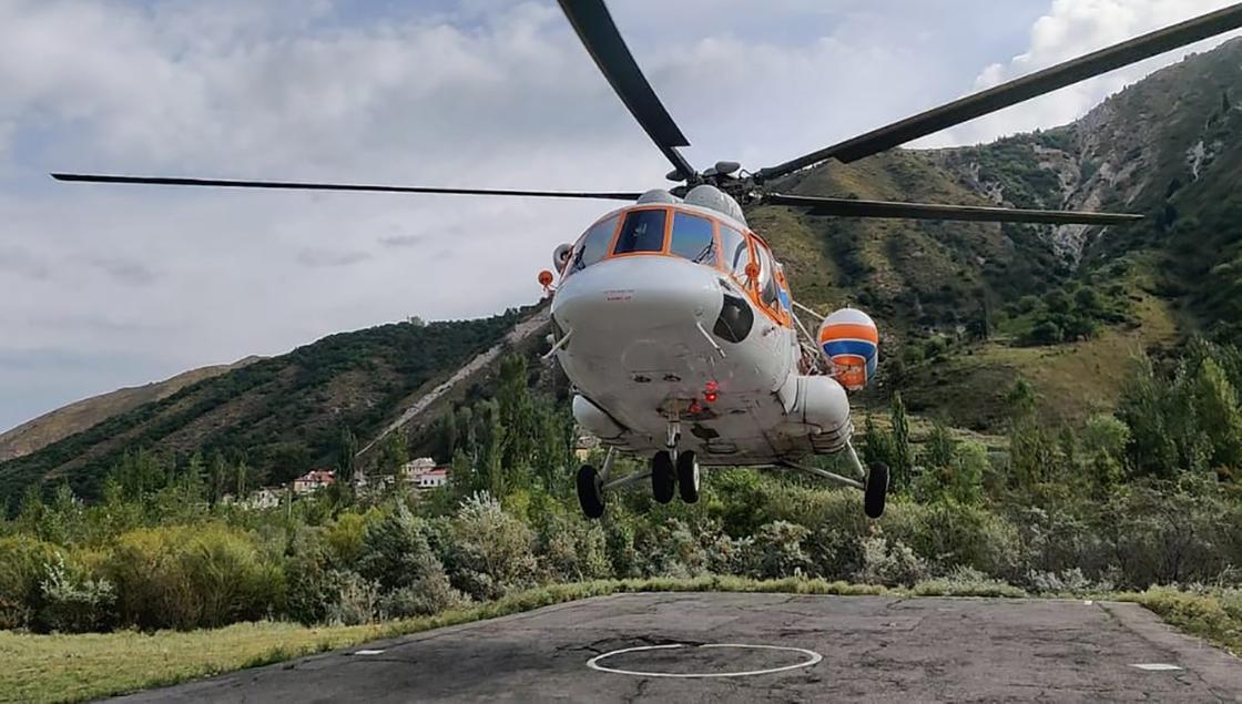 Вертолет взлетает со взлетной площадки в горах