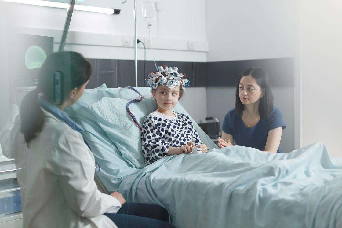 Ребенок на койке в больничной палате с врачом и мамой