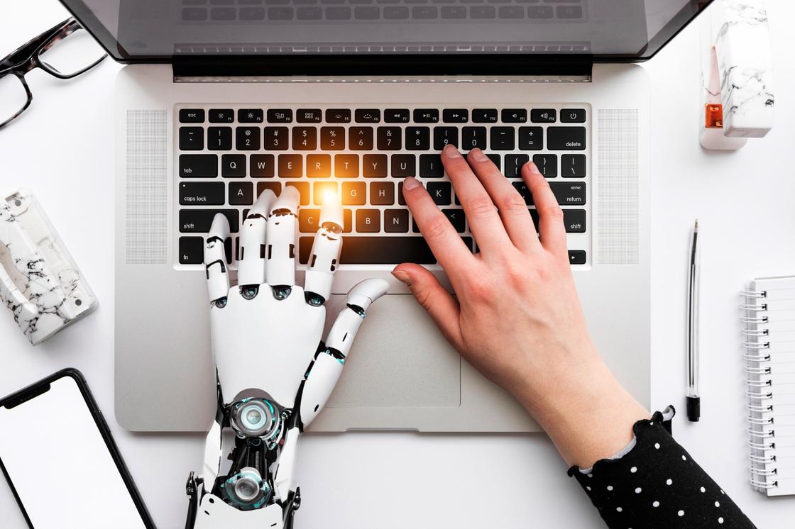 Ноутбук, рука робота и человека