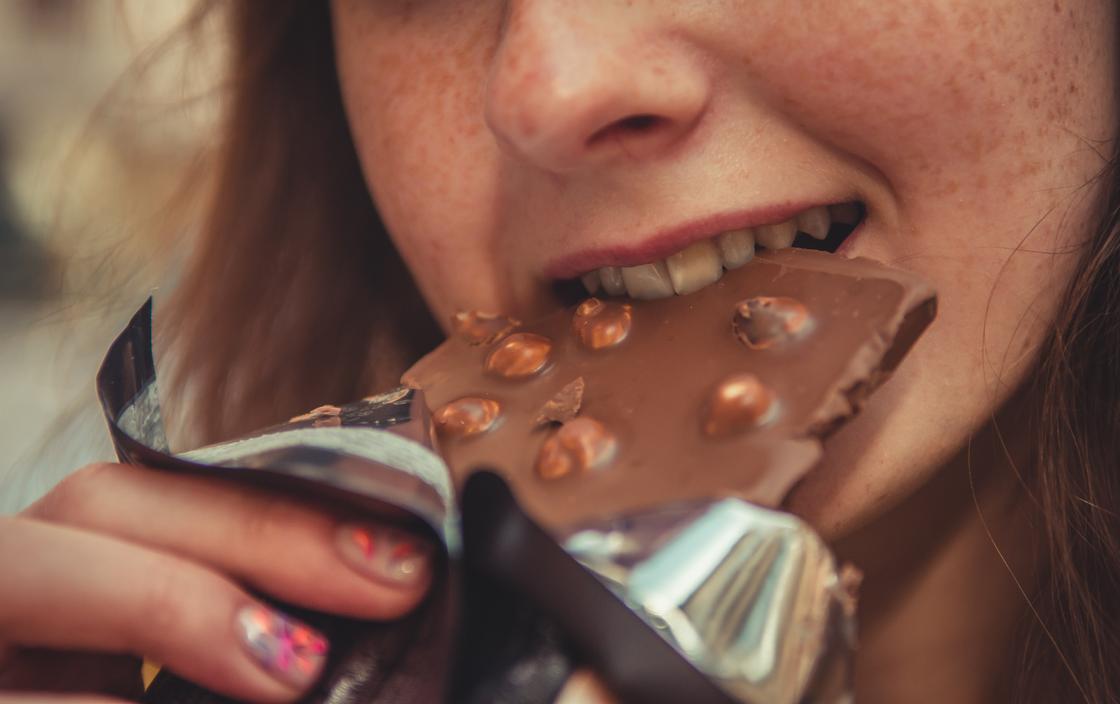 Девушка кусает шоколадку