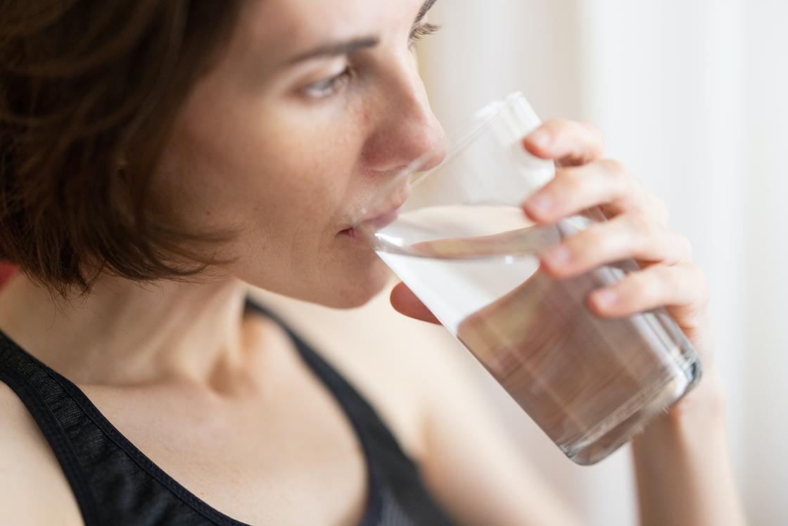 Женщина пьет воду из стакана