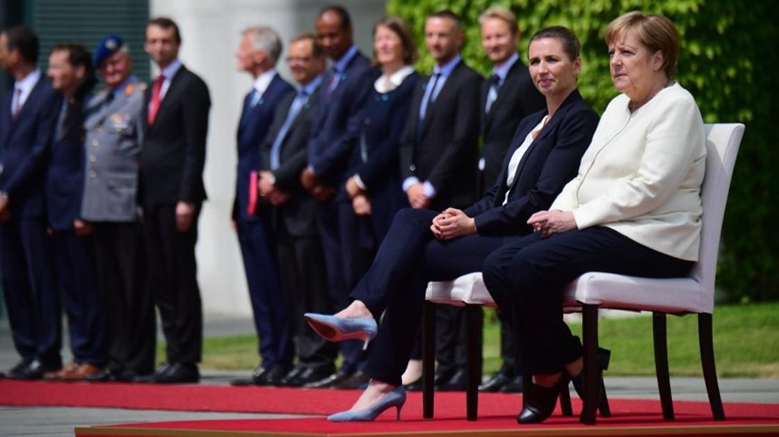 Ангела Меркель пытается преодолеть дрожь и сидит во время гимна