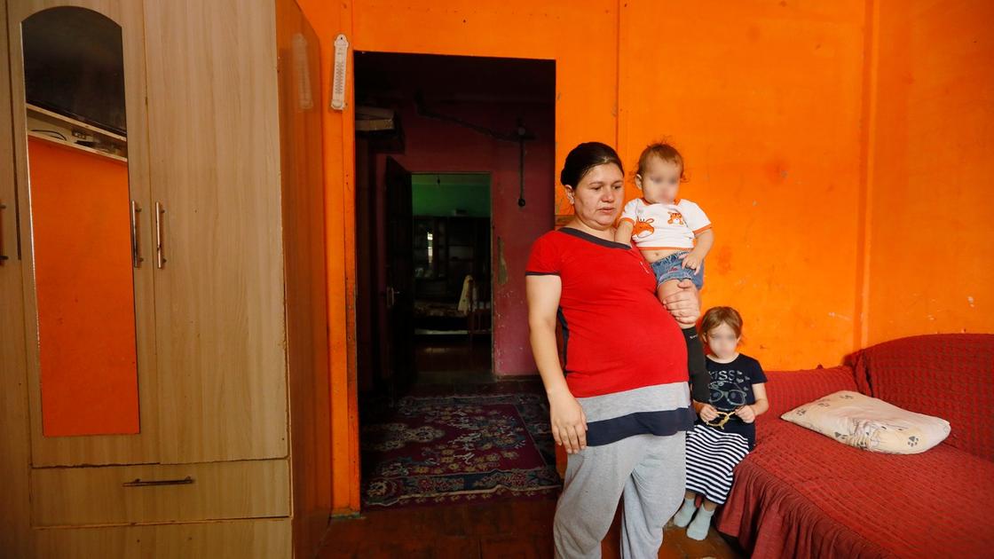 Женщина с ребенком на руках стоит в комнате