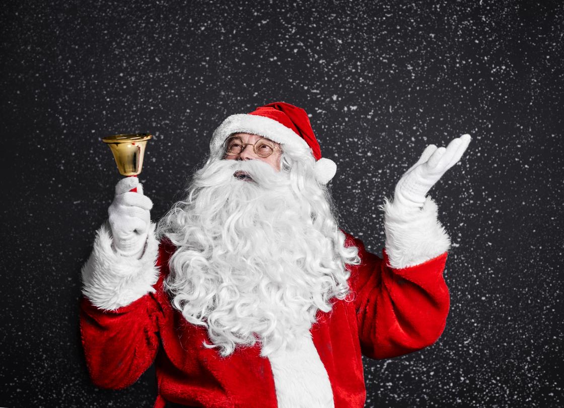 Санта-Клаус держит в руках колокольчик