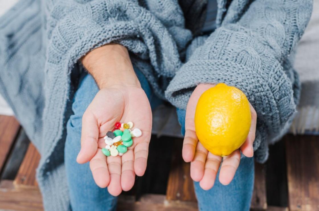 Девушка держит в руке лимон и горсть таблеток