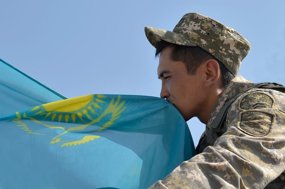 Казахстанский военнослужащий держит флаг Казахстана