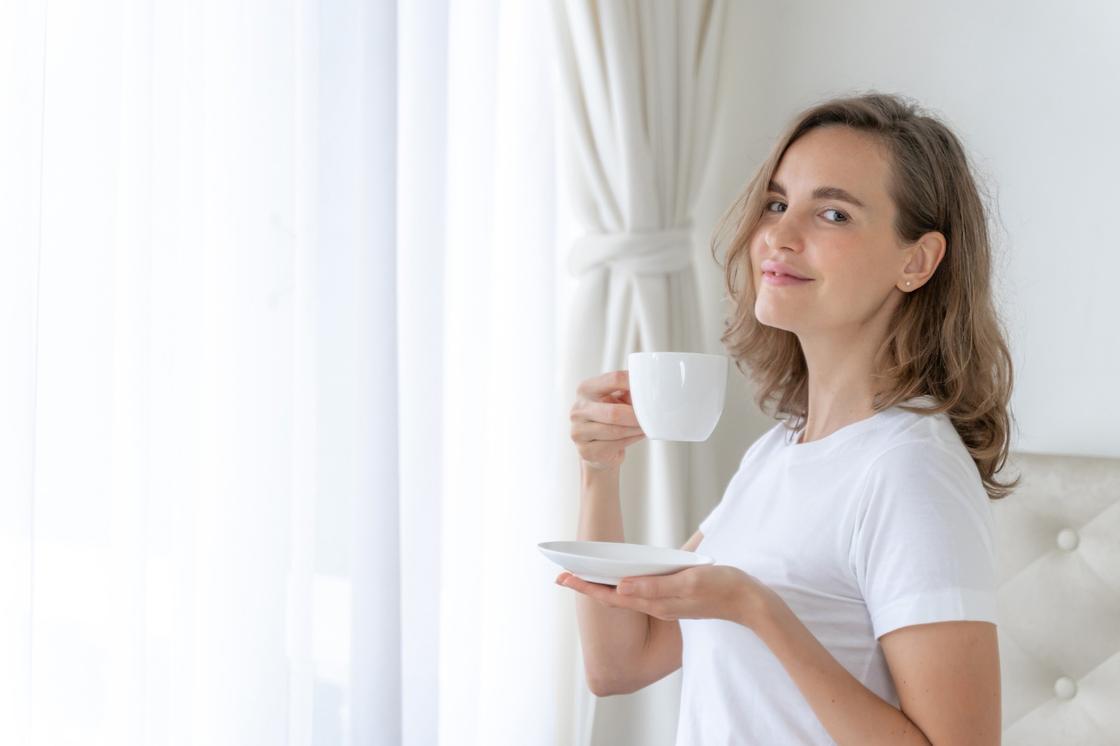 Девушка пьет чай из белой чашки