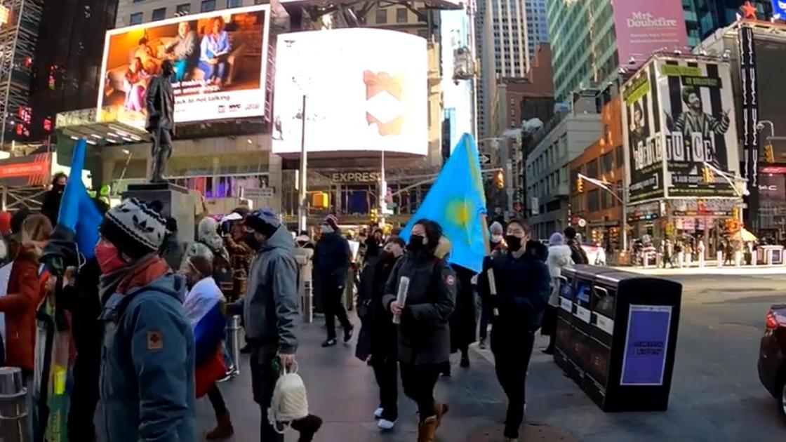 Люди несут в руках флаг Казахстана