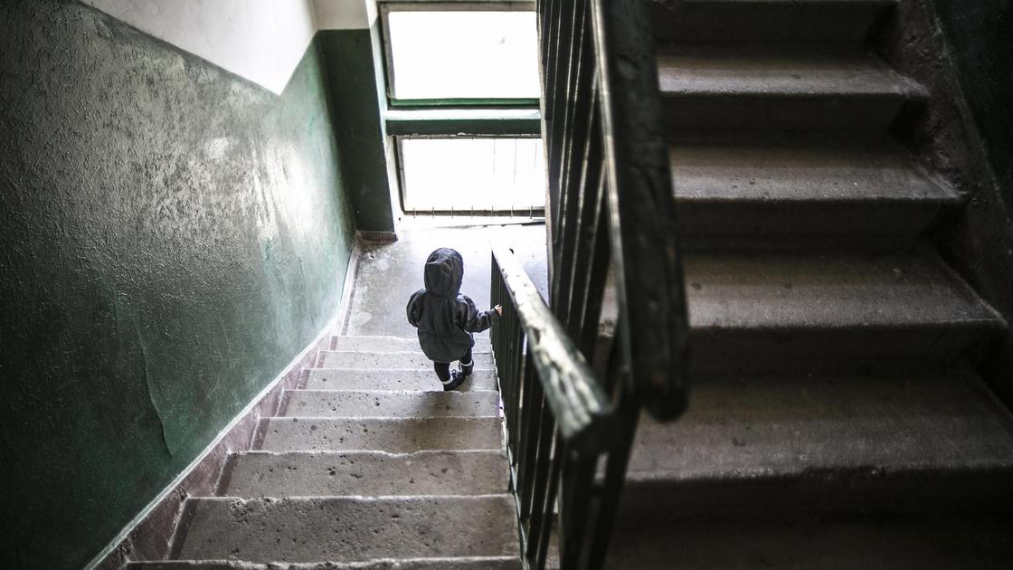 Ребенок идет по лестнице в подъезде многоэтажки