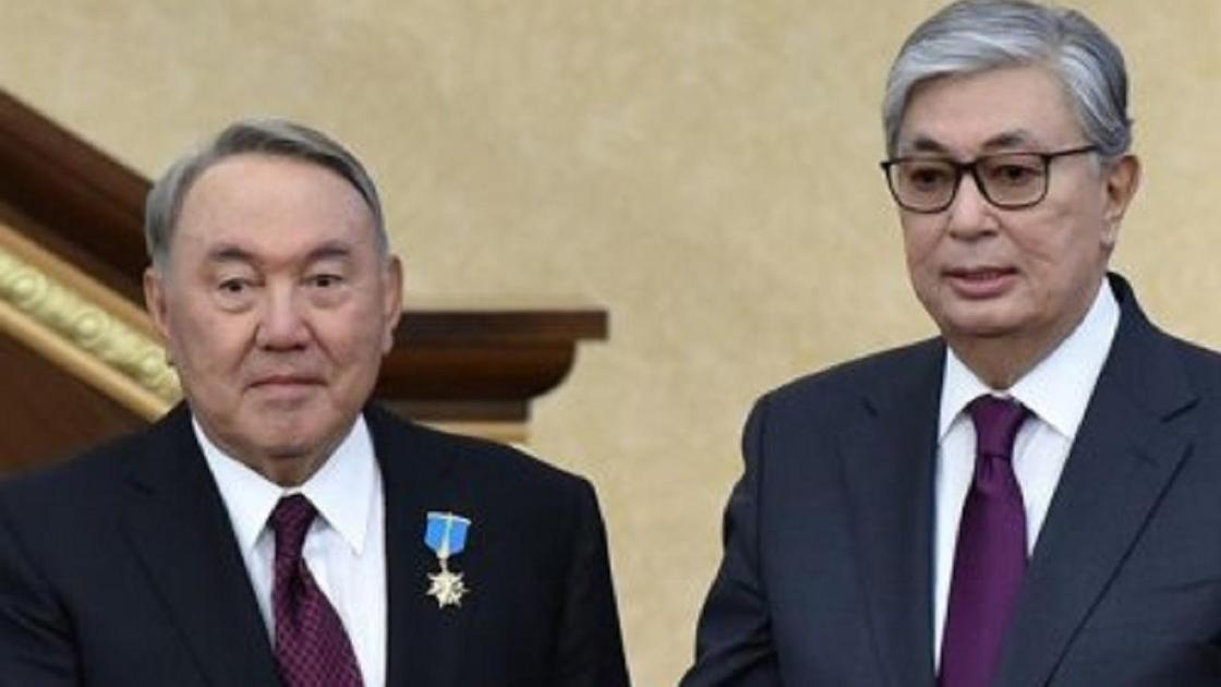 Назарбаев пен Тоқаев қол алысып тұр