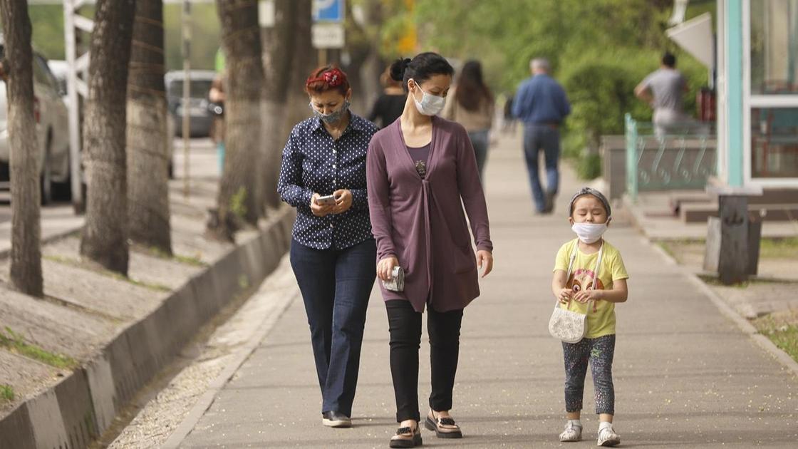 Две женщины и ребенок в медицинских масках идут по городу
