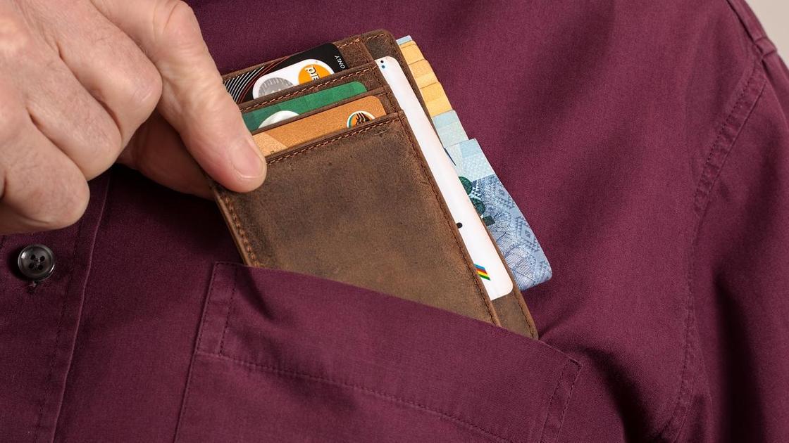 Мужчина кладет бумажник в карман