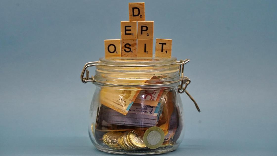 Деньги в баночке и кубики, выстренные в слово "Deposit".