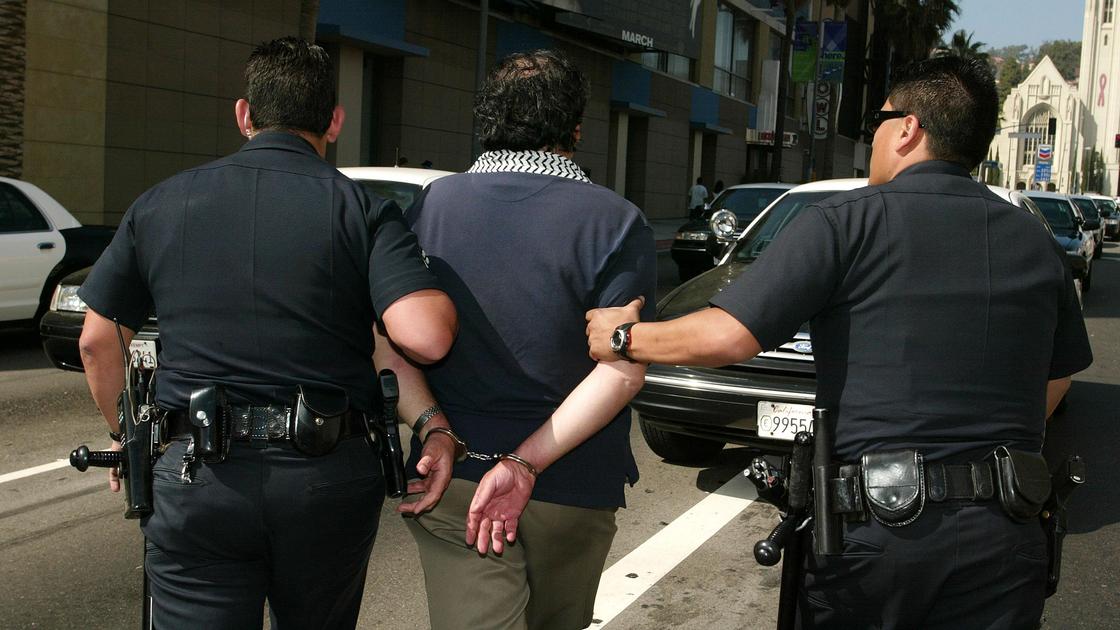 Полицейские ведут мужчину в наручниках