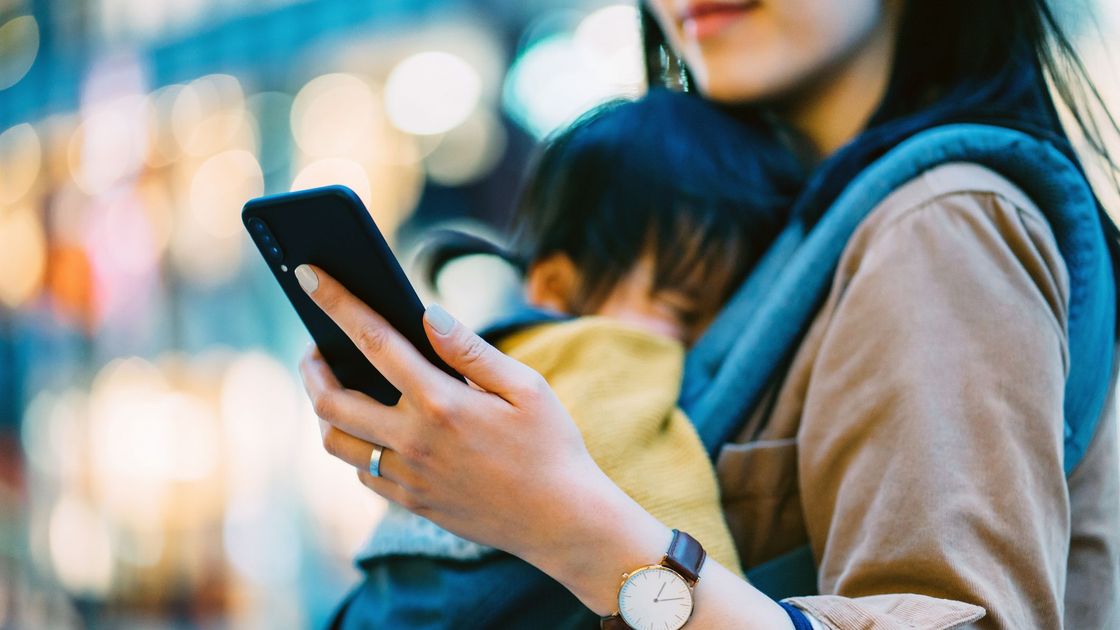 Женщина с ребенком держит в руках телефон