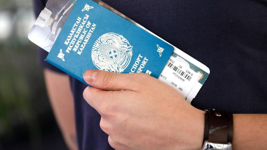 Мужчина держит в руках паспорт с авиабилетом