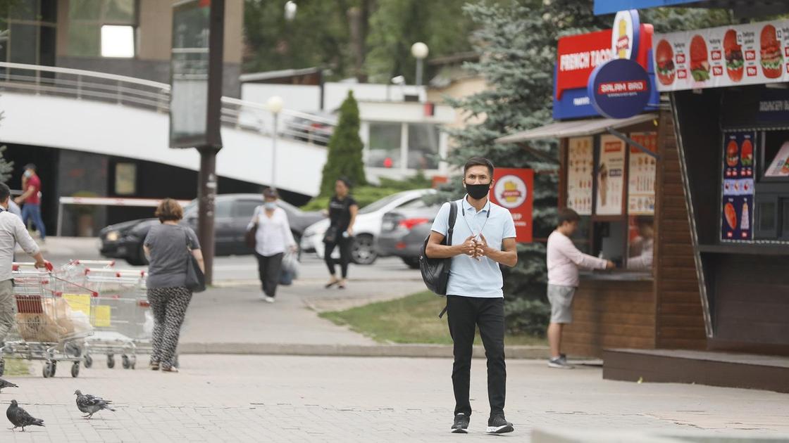 Мужчина в маске идет по улице Алматы