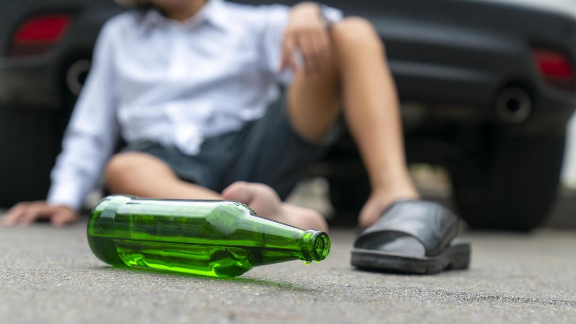 Пьяный водитель сидит возле авто