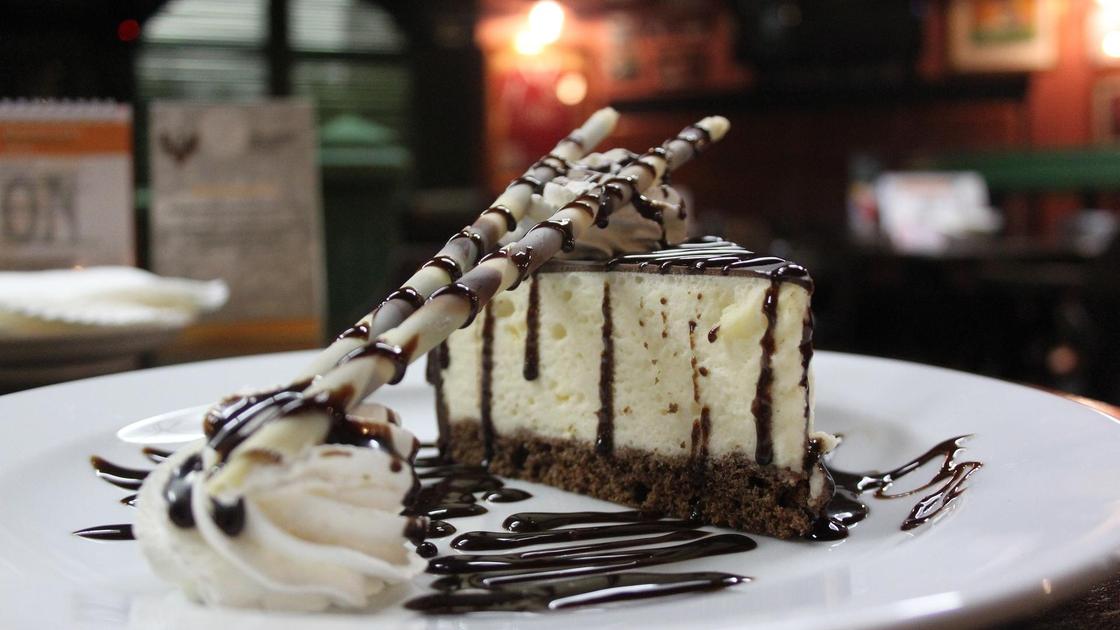 Кусочек торта «Птичье молоко» на сервировочной тарелке с шоколадным декором