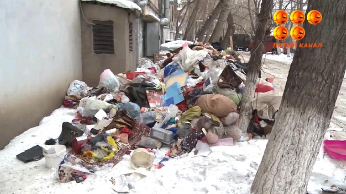 Груда мусора лежит на снегу возле дома