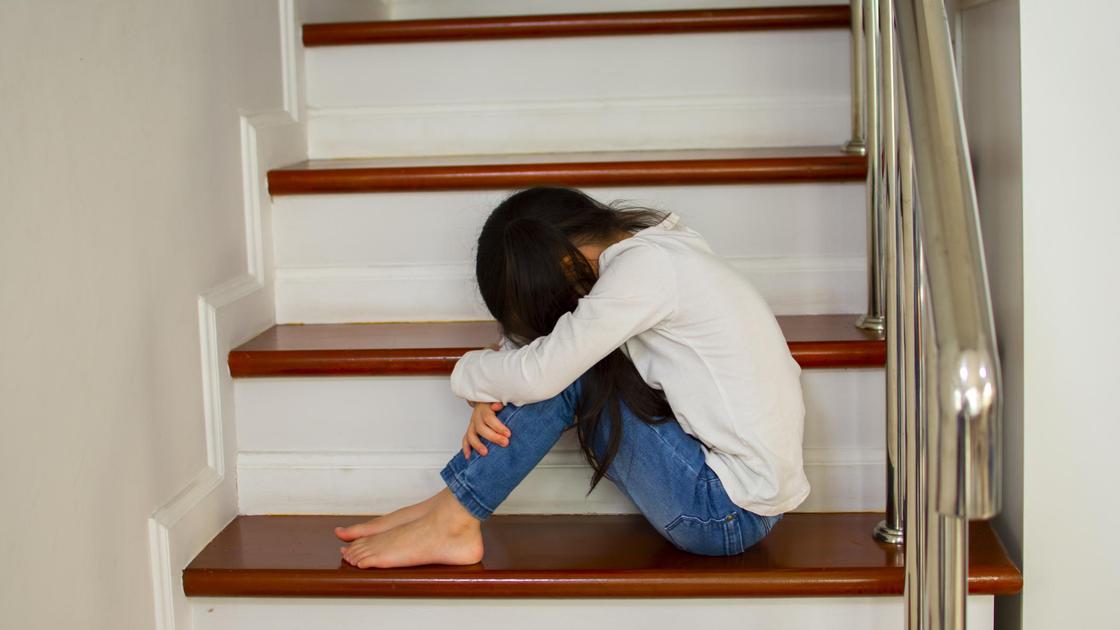 Грустная девочка сидит на лестнице