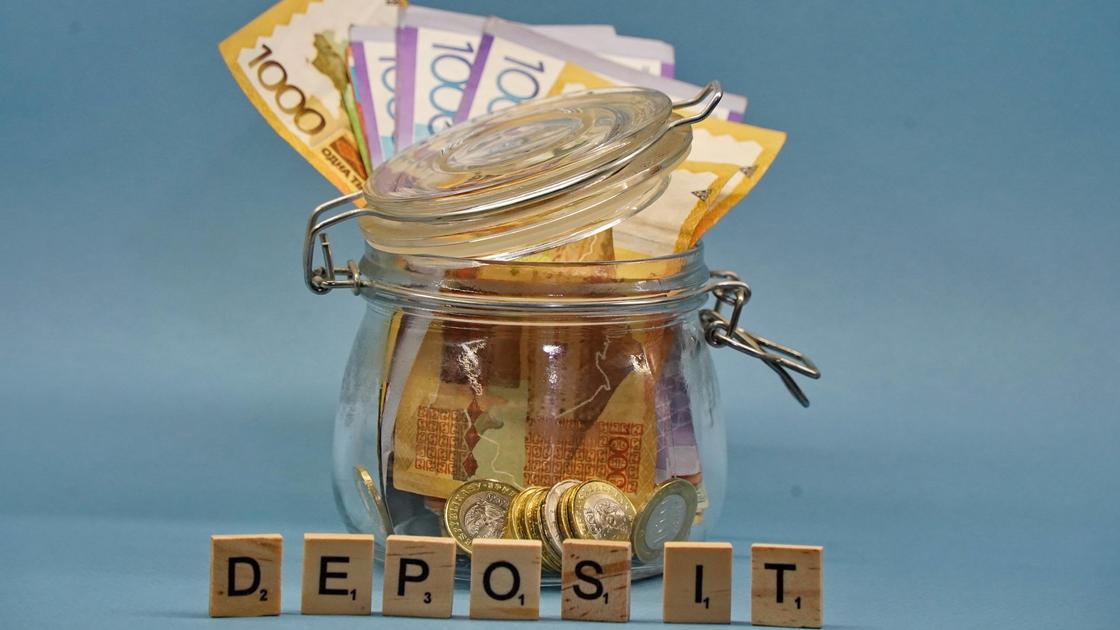 Деньги в баночке и кубики, выстренные в слово "Deposit".