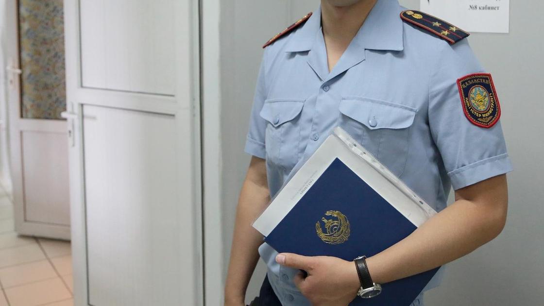 Полицейский в форме стоит в кабинете с документами в руках